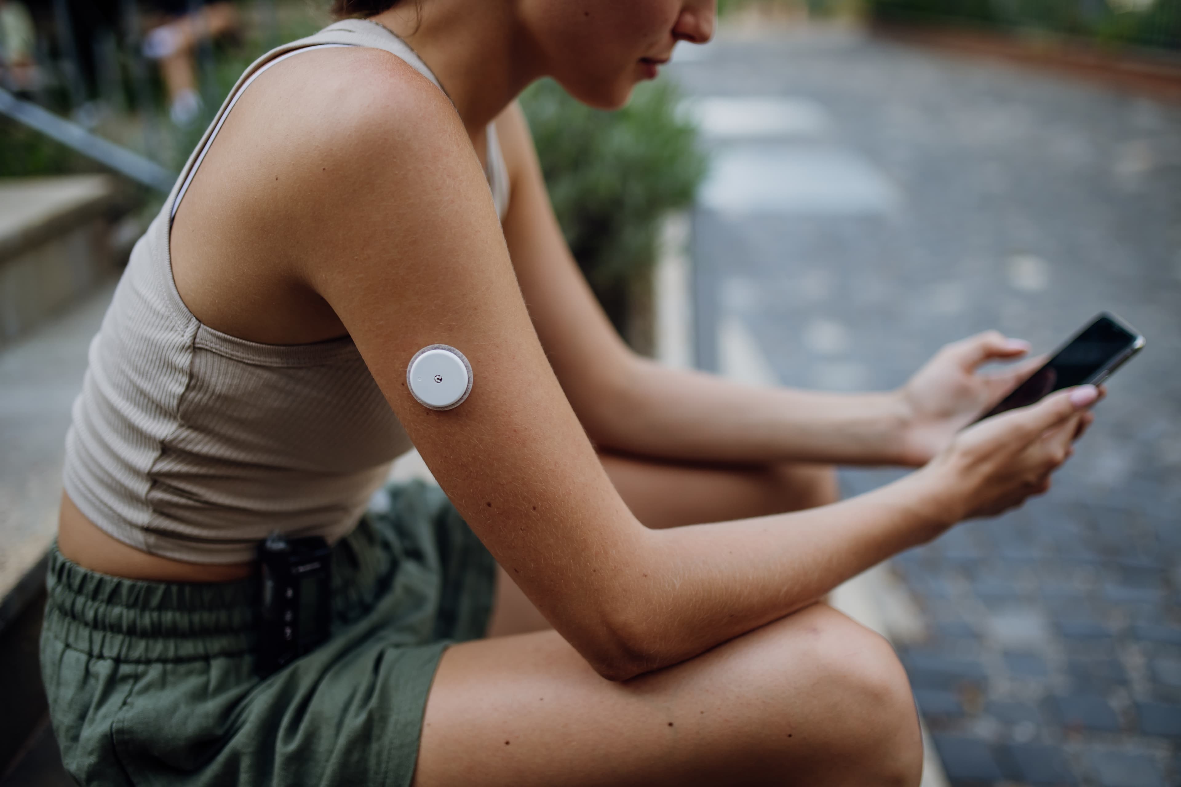 Person wearing a continuous glucose monitor checking their phone